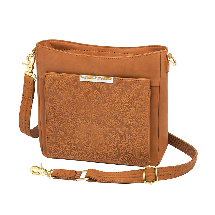 Slim tan concealed carry crossbody bag made from brushed USA cowhide, featuring RFID-blocking front organizer, slash-resistant adjustable strap, and fast-access top-draw gun compartment for left or right-hand draw.