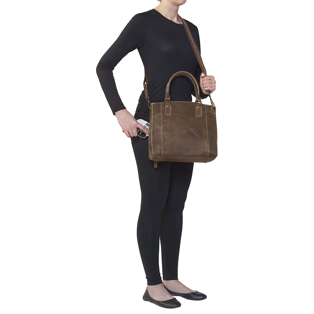 Distressed brown full grain buffalo leather town tote with concealed carry compartment. Vintage-inspired patina develops with use. Features reinforced slash-resistant shoulder strap, padded interior for gun protection, and dual top handles for versatile carry. Designed for ambidextrous draw, includes multiple pockets for phone, pepper spray, and essentials. Tested with popular pistols, equipped with Mernickle holster. Durable and stylish everyday concealed carry purse.