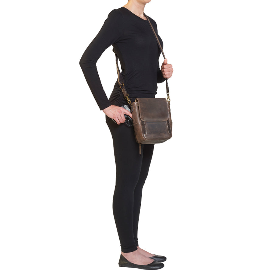 Side view of model drawing handgun from GTM/CZY-80 Distressed Leather Crossbody Satchel illustrating ease of access and ergonomic design for left and right-handed users