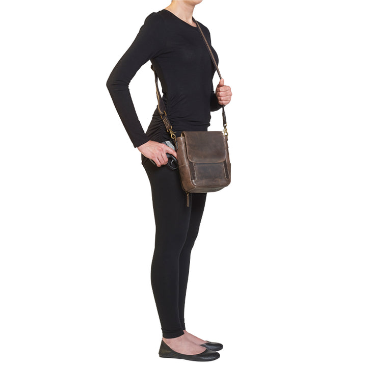 Side view of model drawing handgun from GTM/CZY-80 Distressed Leather Crossbody Satchel illustrating ease of access and ergonomic design for left and right-handed users