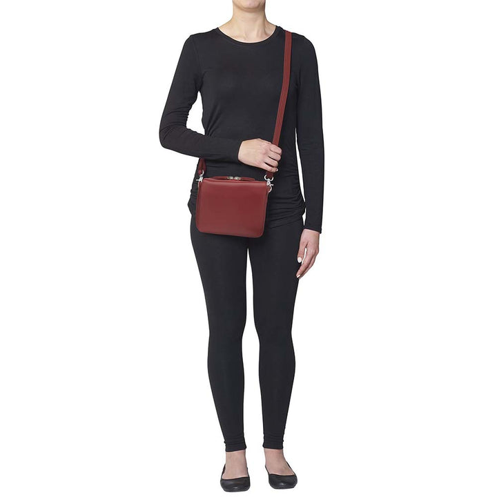 Red compact crossbody organizer concealed carry purse made from soft American cowhide with pebble grain texture, lightweight and durable, featuring RFID-protected zippered pocket, rare earth magnetic flap closure, slash-resistant adjustable shoulder strap with steel wire reinforcement, padded gun compartment, includes mini Mernickle holster, designed for left and right-handed use.