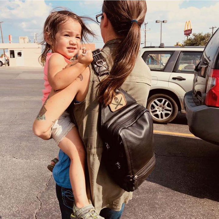 woman with a Black leather concealed carry sling backpack for women and men – lightweight crossbody gun bag with RFID protection, ambidextrous draw, and slash-resistant strap. Fits full-size handguns like Glock 19, Sig P320, VP9. Perfect for EDC, travel, and wheelchair use.