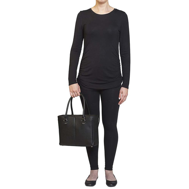 model holding a black timeless Traditional Elegance Concealed Carry Purse with pebble-textured cowhide leather. Features 11-ply steel cable reinforced, slash-resistant carry handles, designed for left or right-handed use. Spacious interior with center zippered divider, leather-trimmed pockets, and zippered pocket. Magnetic snaps close the open top. Includes metal feet for bottom protection. Khaki GTM logo lining for easy visibility. Includes holster compatibility.