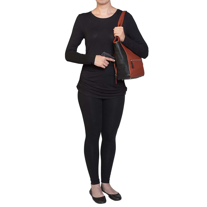 Elegant cinnamon and black leather concealed carry tote with secure underarm fit, reinforced slash-resistant handles, and hidden padded holster pocket. Spacious interior fits iPad, personal items, and compact handguns like Sig P365 or Glock 19.