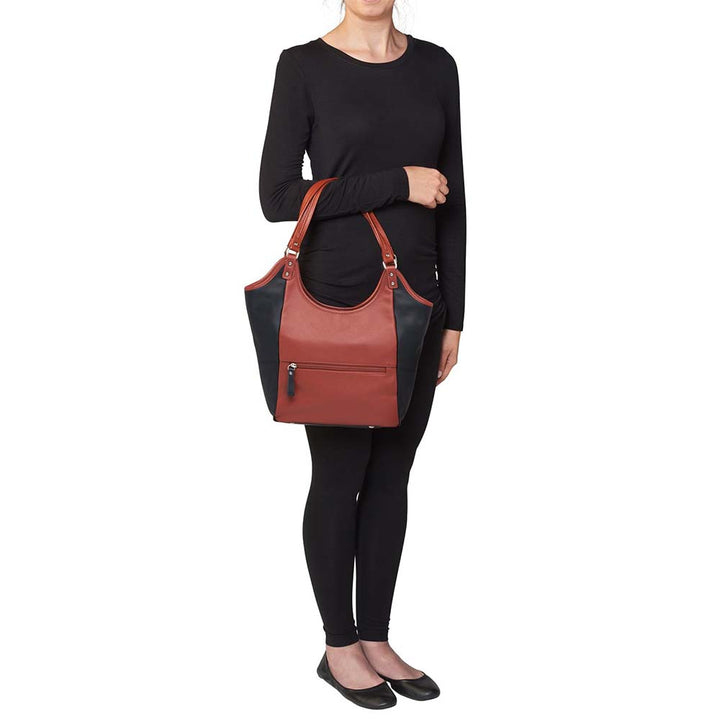 Elegant cinnamon and black leather concealed carry tote with secure underarm fit, reinforced slash-resistant handles, and hidden padded holster pocket. Spacious interior fits iPad, personal items, and compact handguns like Sig P365 or Glock 19.
