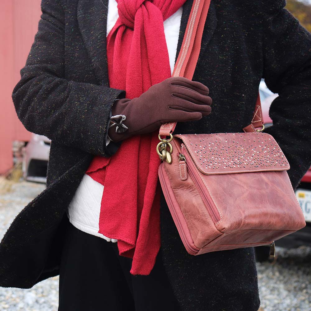 woman tightly carrying a distressed full-grain buffalo leather clutch gets better with age and wear. Designed to fit both left and right-handed carriers, it offers special padding to prevent imprinting and a slash-resistant shoulder strap reinforced with 11-ply steel wire for solid security.