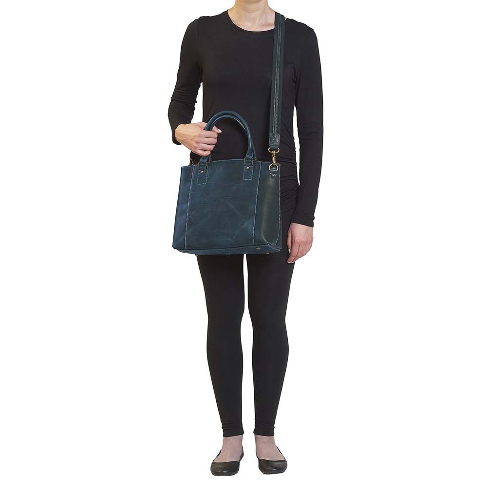 Rich distressed blue leather town tote purse with concealed carry pocket. Made from vintage full grain buffalo leather with soft, worn-in feel that deepens over time. Slash-resistant adjustable crossbody strap with padded gun compartment to prevent imprinting. Includes front and rear zippered pockets, designed for left or right hand draw. Comes with trusted Mernickle holster, perfect for discreet everyday carry with style and durability.