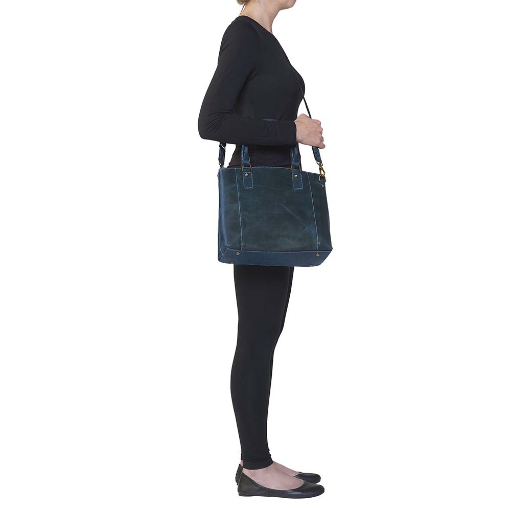 Sophisticated gray distressed full grain buffalo leather concealed carry town tote. Features vintage patina finish that ages gracefully, lightweight yet durable. Equipped with slash-resistant shoulder strap and padded interior for imprint protection. Designed for both left and right handed users, with ample storage including exterior and interior zip pockets. Comes with Mernickle standard holster, tested for reliable concealed carry performance.