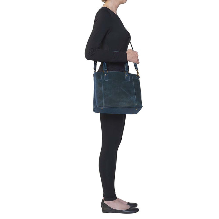 Sophisticated gray distressed full grain buffalo leather concealed carry town tote. Features vintage patina finish that ages gracefully, lightweight yet durable. Equipped with slash-resistant shoulder strap and padded interior for imprint protection. Designed for both left and right handed users, with ample storage including exterior and interior zip pockets. Comes with Mernickle standard holster, tested for reliable concealed carry performance.