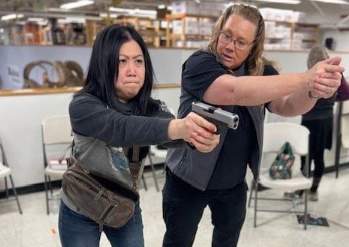 Two women inside a store setting practicing a gun draw maneuver using a GTM concealed carry purse.