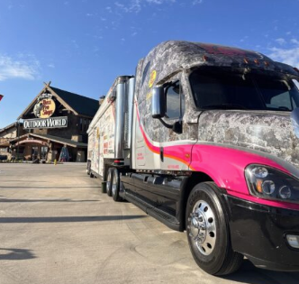 Camo-painted semi truck with pink accents parked outside a Bass Pro Shops store.