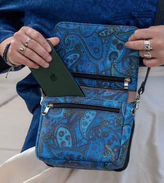  Crossbody Organizer Hands opening a blue paisley-patterned crossbody bag with a phone being placed inside.