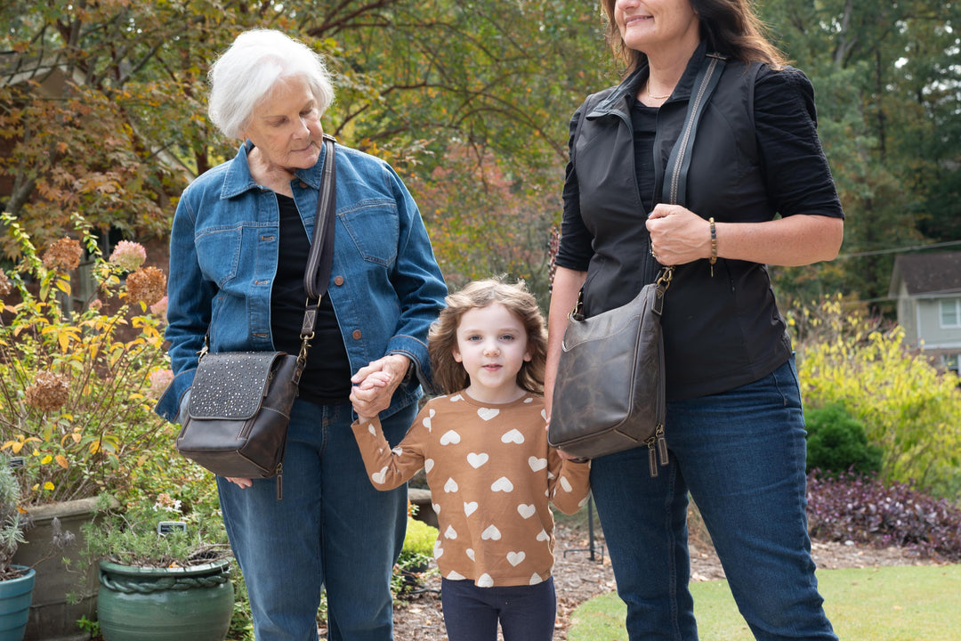 Three generations of women walking outdoors, each carrying a concealed carry handbag.