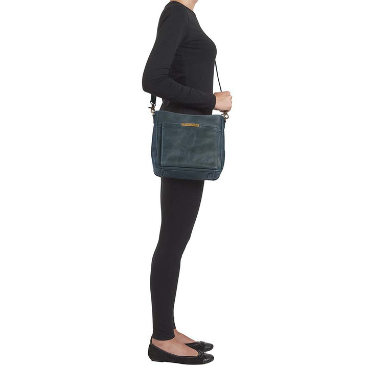 Distressed blue Gun Tote'N Mamas Slim Crossbody Concealed Carry Purse with shoulder strap and concealed carry compartment.