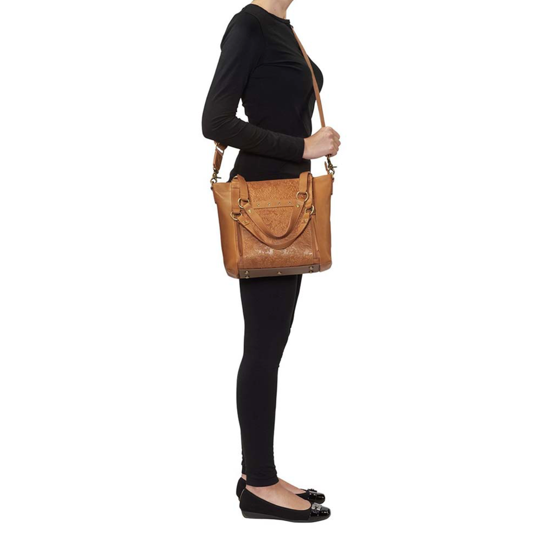 Tan concealed carry BOHO tote purse with top-access CCW compartment, symbolic butterfly and flower debossed leather, slash-proof straps, RFID-blocking zip pocket, and room for compact pistols like CZ P10, M&P Shield, and S&W EZ—each bag uniquely aged from natural tanning.