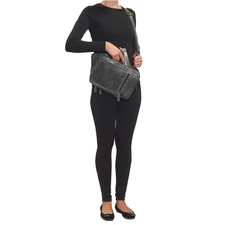model holding gun from Distressed gray buffalo leather sling concealed carry backpack with tactical organization, RFID zip pocket, padded holster compartment for Glock 19, Sig P320, and HK VP9, slash-proof strap, and swing-front crossbody design with 3 exterior zip pockets and morale patch zone